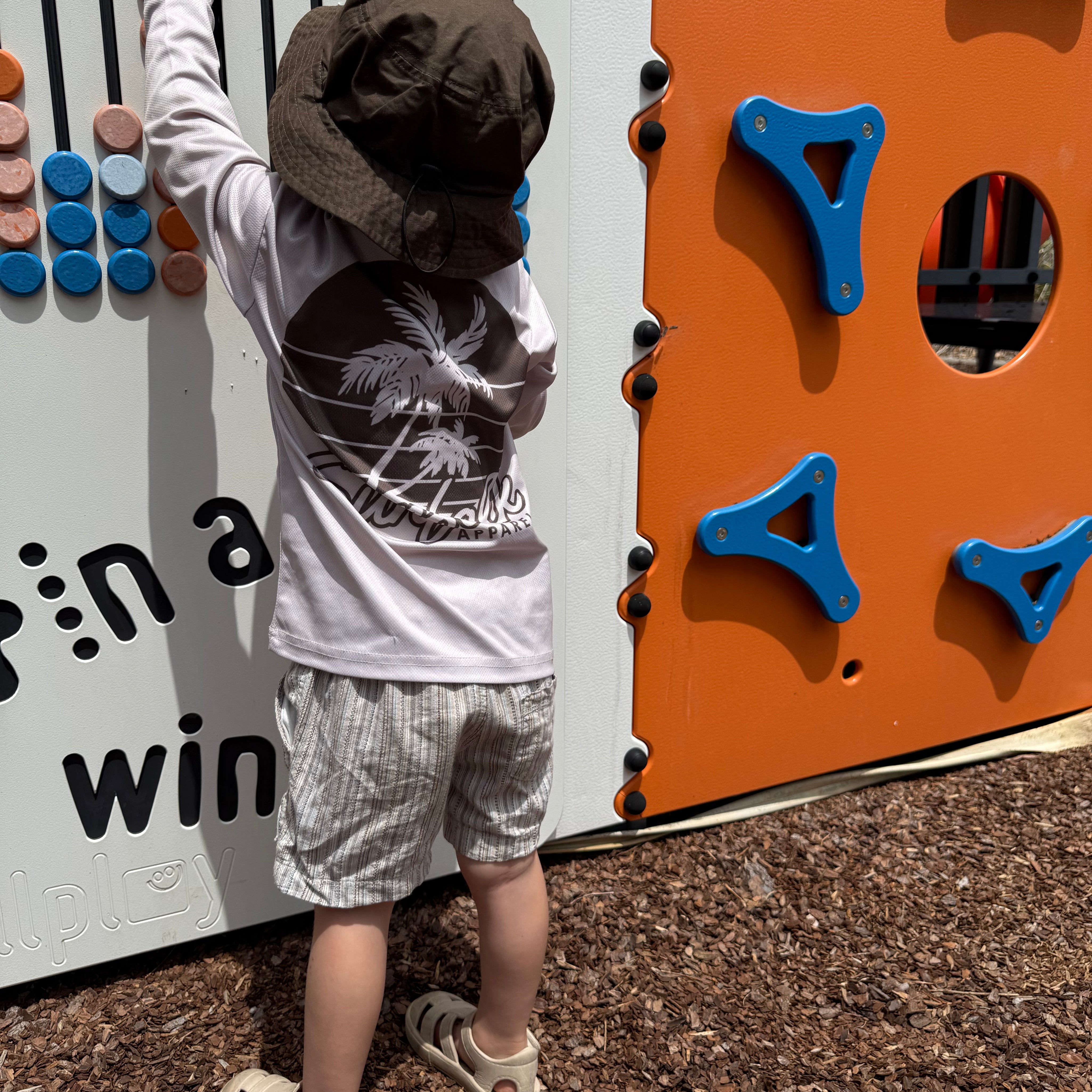 Child playing on a playground climbing wall with colorful holds.