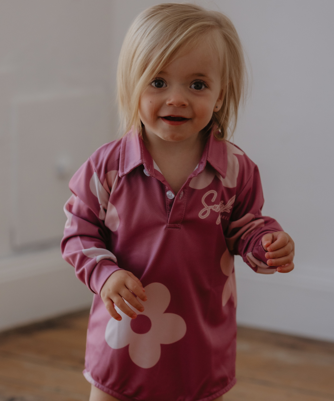Child wearing a pink shirt with floral designs indoors
