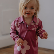 Child wearing a pink shirt with floral designs indoors